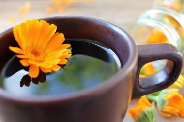 Bitkisel detoks calendula çayı, ahşap arka planda taze çiçekler ve fotokopi alanı. Üst görünüm