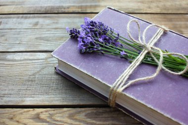 Lavanta çiçekleriyle süslenmiş ve ahşap masaya jüt sicimle bağlanmış eski bir kitap. Uzayı kopyala Seçici odak