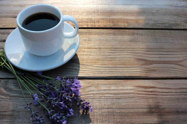 Cup of coffee with lavender flowers on wooden table background with copy space. Summer morning coffee. Top view