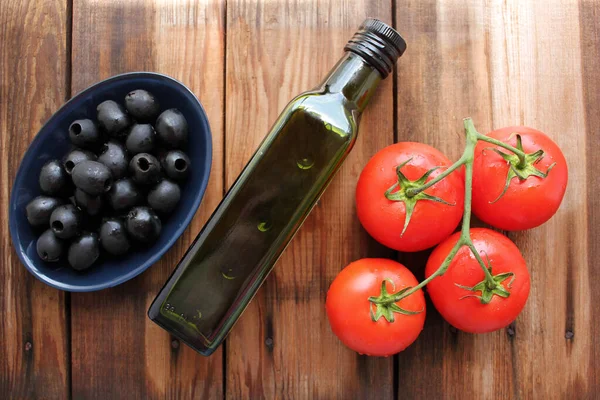 黒いオリーブのボウル ブドウの新鮮なトマト 素朴な木製のテーブルの背景にあるオリーブオイルのボトル パスタやサラダの具材 コピースペース — ストック写真