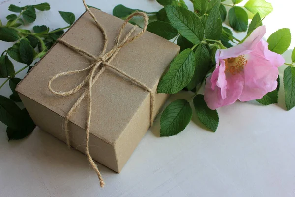 Braune Bastel Geschenkschachtel Mit Rosa Wilden Hagebuttenblüten Auf Altem Holzhintergrund — Stockfoto