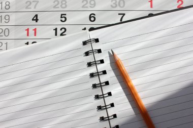 Takvimi kapat ve beyaz sayfalı bir spiral ve tahta beyaz pencere pervazında bir kalem aç. Üst görünüm, alanı kopyala