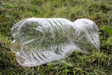 Yağmurdan sonra çimlerin üzerine şeffaf plastik şişe boşalt. Plastik atık konseptiyle çevre kirliliği. Üst Manzara. Boşluğu kopyala