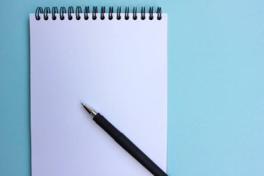 Siyah kalemle kağıt defteri aç. mavi arka planda. Okul konseptine geri dönelim. Düz yat, boşluğu kopyala