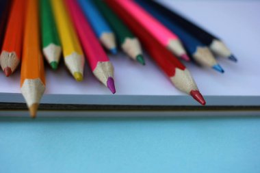 Mavi arka planda renkli kalemlerin ve defterlerin üst görüntüsü. Okul konseptine dönelim.