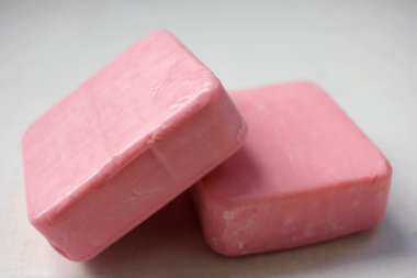 Beyaz ahşap arka planda iki kalıp pembe ev yapımı sabun. Seçici odak, boşluğu kopyala