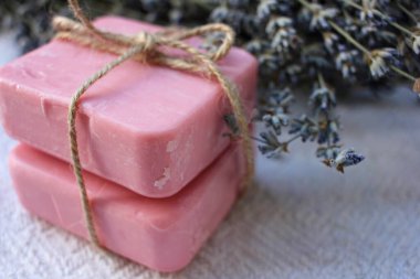 Beyaz ahşap arka planda iplik ve lavanta çiçekleri ile bağlanmış iki kalıp pembe el yapımı sabun. Seçici odak, boşluğu kopyala