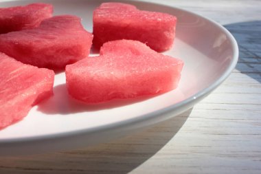 Kalbinde karpuz dilimleri var. Tahta masada beyaz bir tabakta. Üst görünüm, alanı kopyala.