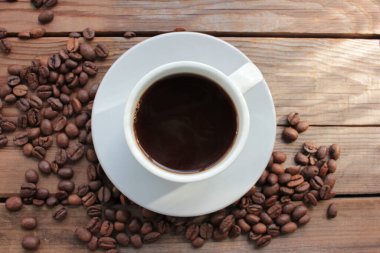 Yukarıdan kahve ve fasulye. Sade kahve ve ahşap masada dağınık kahve çekirdekleri. Düz konum.