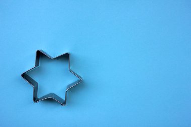 Gümüş Noel yıldızı şekilli kurabiye kesici mavi arka planda fotokopi alanı ile.