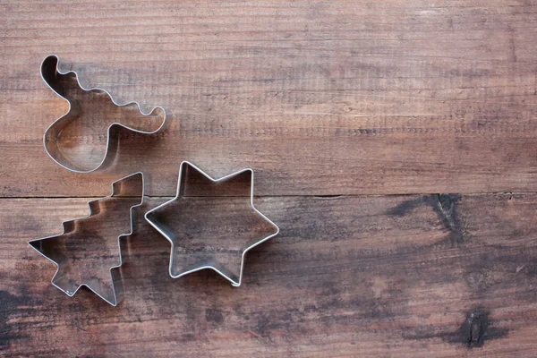 Noel ağacı, yıldız ve geyik şekilli kurabiye kesiciler ahşap bir masada. Noel arkaplanı. Üst görünüm, alanı kopyala