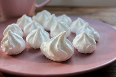 Pembe bir tabakta kremalı pasta yakın plan. Pembe arka planda şekerlemeler, seçici odaklanma