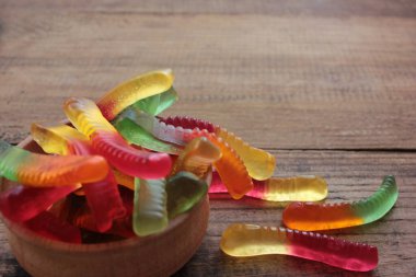 Halloween gummy worms in a bowl. Colorful jelly worms shaped candies. Top view, selective focus clipart