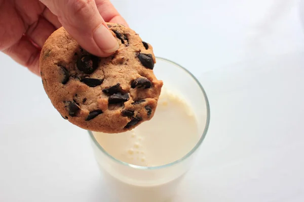 Weibliche Hand Taucht Schokoladenkekse Ein Glas Milch Auf Weißem Hintergrund — Stockfoto