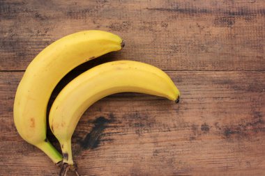 Ahşap arka planda muzlar. Kırsal masada olgun doğal meyvelerin manzarası