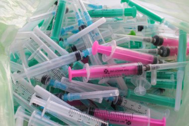 Tıbbi atık. Kullanılan tek kullanımlık şırınga yığını beyaz arka planda plastik torba içinde. 