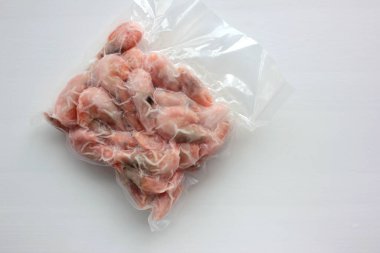 Kaynamış ve donmuş karidesler vakum şeffaf plastik ambalaj torbasında beyaz arka planda.