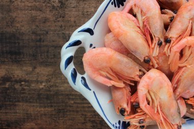 Tabakta pişmiş pembe karides. Kabuklu Kuzey Atlantik karidesleri kırsal ahşap masada kasede. Üst görünüm, alanı kopyala