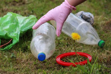 İnsan gezegeni plastiğin kirliliğinden kurtarıyor. Karahindiba filizi ve yeşil çimlerin üzerinde şişe. Dünya 'yı çürüyen plastik bozulmasından koru