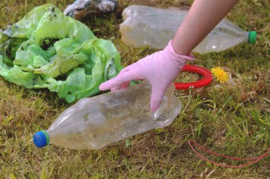 İnsan gezegeni plastiğin kirliliğinden kurtarıyor. Karahindiba filizi ve yeşil çimlerin üzerinde şişe. Dünya 'yı çürüyen plastik bozulmasından koru