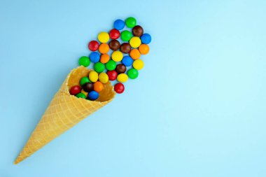 Mavi arka planda waffle külahlı çok renkli şekerler.