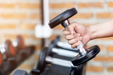 Spor salonunda bir adamın eli, sağ eliyle bir dambılı tutarken egzersiz ve sağlık hizmetleri kavramını göz önünde bulundurun..