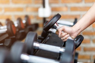 Spor salonunda bir adamın eli, sağ eliyle bir dambılı tutarken egzersiz ve sağlık hizmetleri kavramını göz önünde bulundurun..