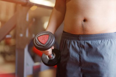 Şişman bir adam, şişman bir adamın elinde spor salonunun arka planında izole edilmiş aşırı göbek yağı, şişman bir adamın şişman göbeği, insan diyeti yaşam tarzı konsepti, göbeği ve sağlıklı mide kaslarını geliştirmek için..