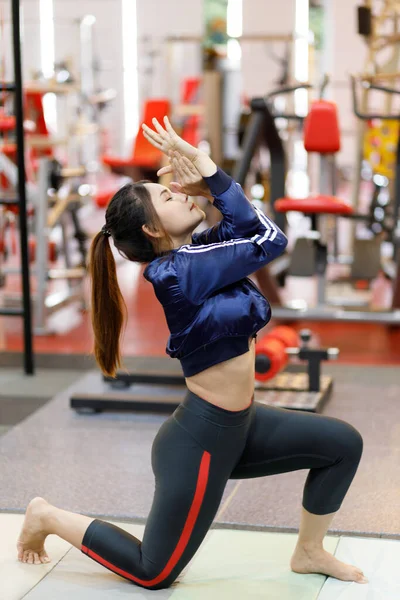 Sporty young woman doing yoga practice in the gym - concept of healthy life and natural balance between body and mental development.
