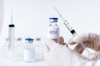 Coronavirus aşısı COVID-19 'un geliştirilmesi ve yaratılması. Doktor beyaz aşı kavanozu ve şırınganın elinde Coronavirus aşısı kavramı. Koronavirüsle mücadele aşısı. Sağlık ve Tıp Konsepti.