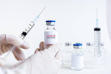 Coronavirus aşısı COVID-19 'un geliştirilmesi ve yaratılması. Doktor beyaz aşı kavanozu ve şırınganın elinde Coronavirus aşısı kavramı. Koronavirüsle mücadele aşısı. Sağlık ve Tıp Konsepti.