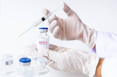 Coronavirus aşısı COVID-19 'un geliştirilmesi ve yaratılması. Doktor beyaz aşı kavanozu ve şırınganın elinde Coronavirus aşısı kavramı. Koronavirüsle mücadele aşısı. Sağlık ve Tıp Konsepti.
