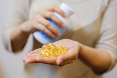 Kavanozdan ele balık yağı kapsülleri olan güzel bir kadına yaklaş. Spor, sağlıklı yaşam tarzı, ilaç, besin takviyeleri, insan kavramı ve sağlıklı kavramlar.
