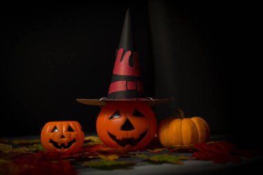 Cadılar Bayramı cadı şapkası takan bir balkabağı. Akçaağaç yapraklı..