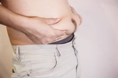 Şişman adam, şişman adam, beyaz arka planda fazla göbek yağı, şişman adam göbeği, insan diyeti yaşam tarzı konsepti göbeği ve sağlıklı mide kaslarını şekillendirmek için..