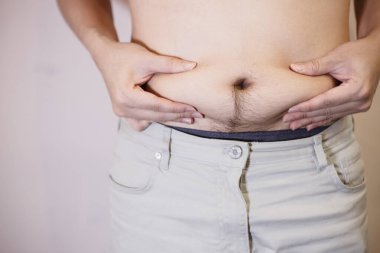 Şişman adam, şişman adam, beyaz arka planda fazla göbek yağı, şişman adam göbeği, insan diyeti yaşam tarzı konsepti göbeği ve sağlıklı mide kaslarını şekillendirmek için..