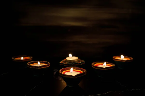 Mutlu Diwaliler - Dipavali sırasında Clay Diya lambaları yandı, Hindu ışık festivali kutlaması. Koyu arka planda renkli geleneksel gaz lambası diya. Metin için alanı kopyala.