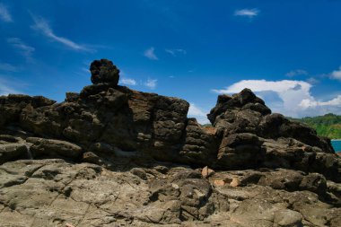 Gündüz kumsalın doğal manzarası. Yogyakarta Endonezya 'nın güney kıyısındaki bulutlu mavi gökyüzüne karşı dalgalara meydan okuyor gibi..