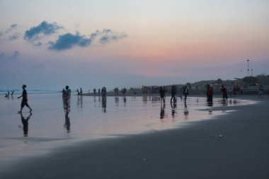 Sahilin manzarası ve öğleden sonra dalgalar, gün batımı sarı bir ışık yayar, birçok insanın sahildeki manzaranın tadını çıkardığını görürdüm.