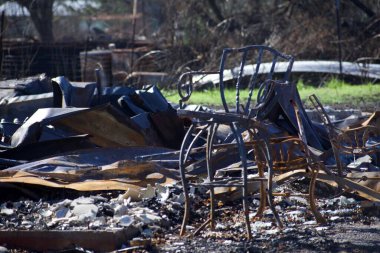 Ön planda yanmış sandalyeler Oregon 'daki yangınlar yüzünden artık mevcut olmayan bir ev düzeni üzerinde oturuyorlar..