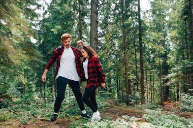 Genç bir adam bir kızın ormanda dağ yürüyüşünde elini kaldırmasına yardım ediyor. Adam kızın elini tutuyor ve yürüyüş yaparken kızın ormanı geçmesine yardım ediyor. Çift aktif olarak dağlarda dinleniyor.
