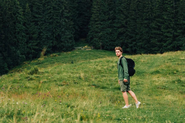 Νεαρός Άνδρας Σακίδιο Περπατάει Στα Βουνά Καλοκαίρι Γυρίζει Πίσω Εξετάζοντας — Φωτογραφία Αρχείου