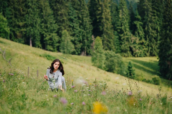 Menina Positiva Vestido Azul Senta Grama Nas Montanhas Coleta Flores — Fotografia de Stock