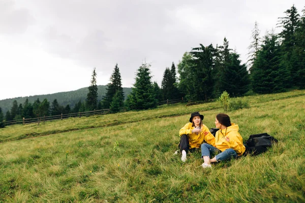 Duas Meninas Turistas Capas Chuva Amarelas Sentadas Prado Nas Montanhas Imagens De Bancos De Imagens Sem Royalties
