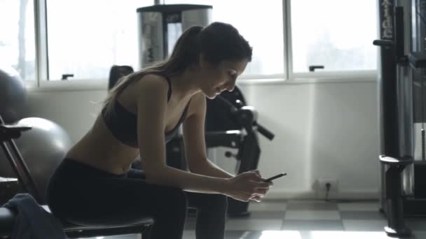 妇女在健身房休息和使用她的电话 — 图库视频影像