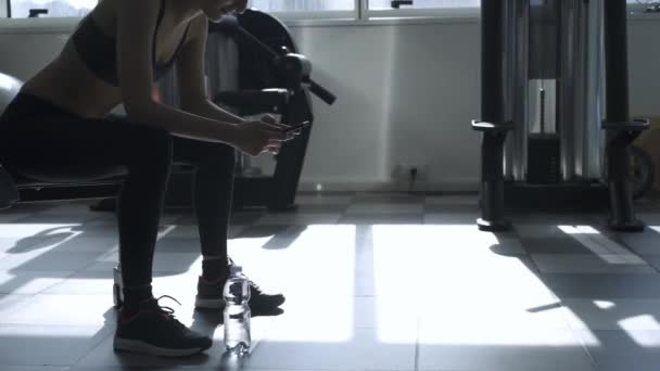 Frau macht Pause im Fitnessstudio und benutzt ihr Handy — Stockvideo