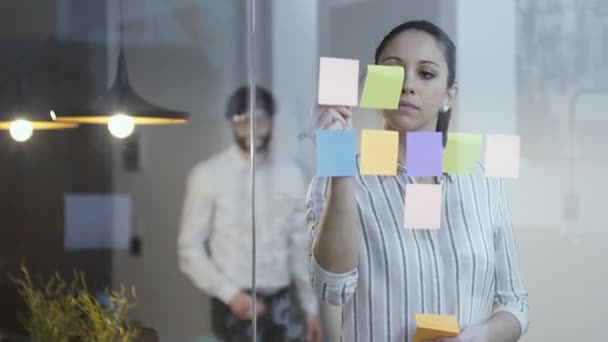 Młoda kobieta interesu pisanie notatki programu Sticky Notes — Wideo stockowe