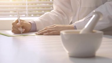 Laboratuvarda çalışan ve bir reçete, harç ve havaneli ile ön plan, tıp ve eczacılık konsepti üzerine yazma profesyonel eczacı