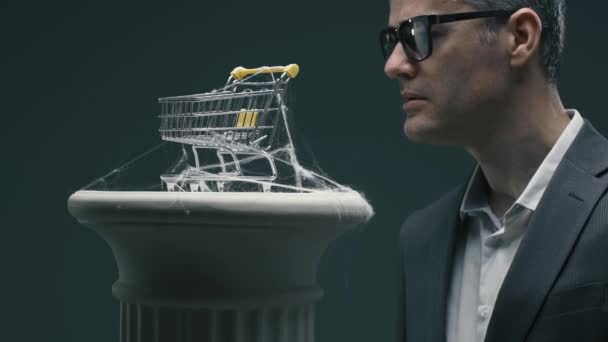 Disappointed Business Executive Blowing Dusty Miniature Shopping Cart Cobwebs Unsuccessful — Stock Video