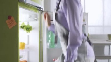 Genç kadın mutfakta yemek hazırlama buzdolabı, sağlıklı yaşam ve beslenme kavramı üzerinden taze sebze alıyor